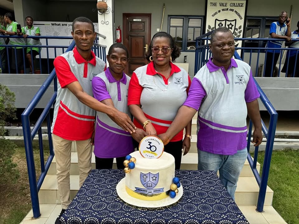 Vale College staff celebrating together beside an anniversary cake